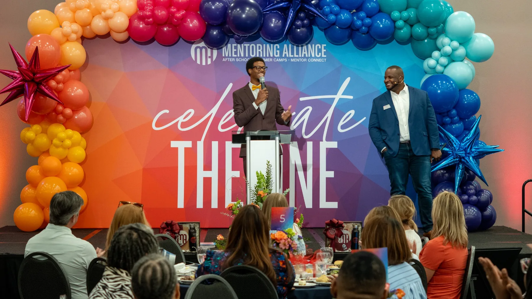 Ian Wade speaking on stage as an event MC for Mentoring Alliance